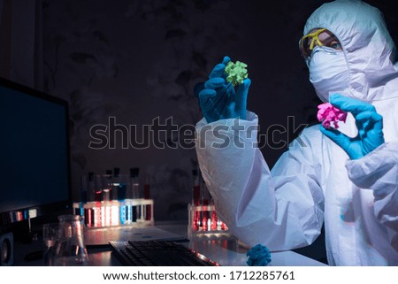Close-up of woman in protective costume and protective gloves working with test tubes with colored liquid at the home lab