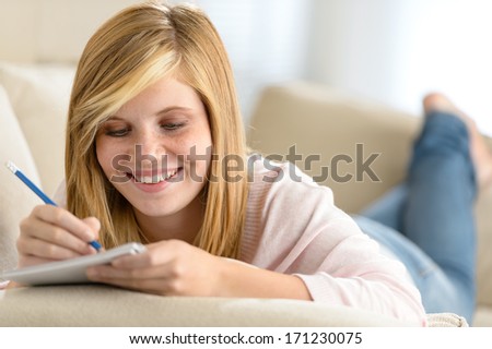 Beautiful teenage girl lying on sofa writing notes in diary Royalty-Free Stock Photo #171230075