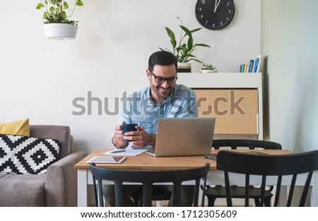 Handsome young man working on laptop computer at home stock photo