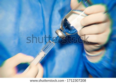 Male doctor hands with gloves takes medicine in a syringe. Medical worker doctor taking a large number of patients due to the epidemic of coronavirus. Medicine COVID-19 concept