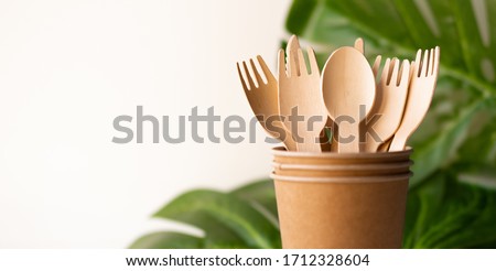 bunner eco friendly disposable kitchenware utensils on white background. wooden forks and spoons in paper cup. and green leaf. ecology, zero waste concept. copyspace. Royalty-Free Stock Photo #1712328604