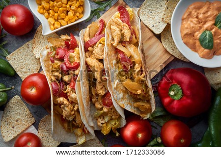 Still life of three fajitas or Mexican tacos with meat, pepper, tomato, spicy pepper and nachos. Mexican food concept.
