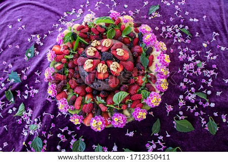 Birthday cake in chocolate with strawberries, blueberries and banana on purple background. Top view. Picture for a menu or a confectionery catalog
