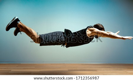 A man does functional exercises in the gym on a gray background. Fitness concept, sports body, body positive, copy space Royalty-Free Stock Photo #1712356987