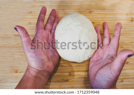 fresh raw dough in bakers hands isolated on wood background