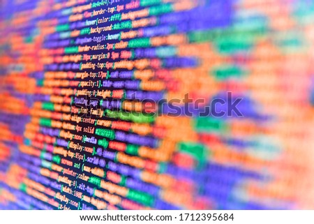 Programmer working on computer screen. Lots of digits on the computer screen. Close up of computer web page code inside of html file. Code on dark background. Abstract computer script source code. 