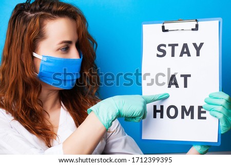 Woman holding blank with inscription stay at home calling for stop spreading covid-19