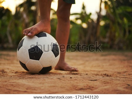 Close up picture of an old ball and foot of a boy who is playing football. Picture with copy space.