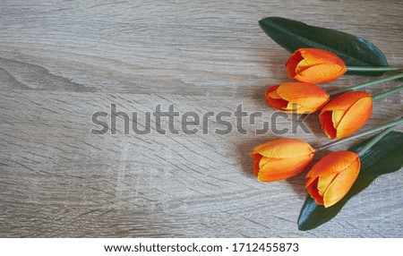 Beautiful orange tulips on woonden background, top view.