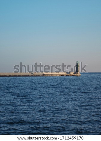 Concrete pier with a lighthouse in a marina