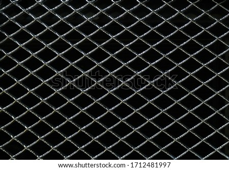 Steel grating with gloss on a black background. Seamless texture metal wire fence. Image for using the backdrop. 