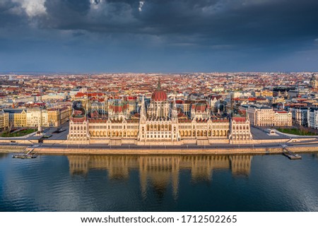 Budapest, Hungary - Aerial view of the beautiful Hungarian Parliament building with reflection and warm golden sunlight at sunset. The streets are totally empty due to the 2020 Coronavirus quarantine Royalty-Free Stock Photo #1712502265