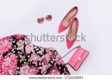 Woman fashion sundress with floral pattern and pink handbag, sunglasses, pink high hell shoes on white background 
