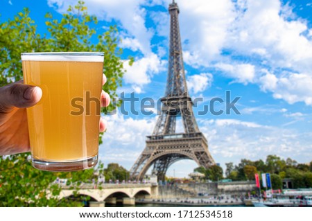 Man holding glass of light beer on Eiffel tower background, Paris France