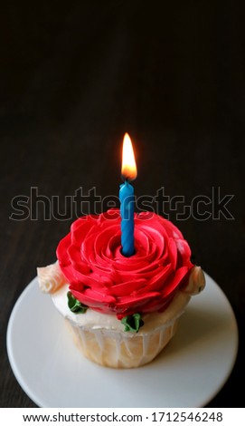 Lovely birthday cake decorated with red rose shaped whipped cream with a shining candle