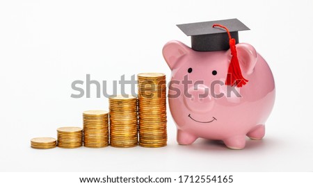 Piggy bank in graduate cap near stack of coins. Savings for education. Higher education prices. Isolated on white background. Royalty-Free Stock Photo #1712554165