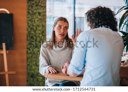 Young man and woman smiling and having a pleasant conversation at the coffee bar