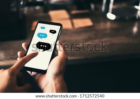 Woman hand using smart phone at coffee shop with chat icon flying abstract background. Technology business and freelance concept. Vintage tone filter effect color style.