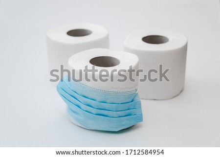 Four rolls Quality and beautiful toilet paper on white background and near are protective masks from coronavirus