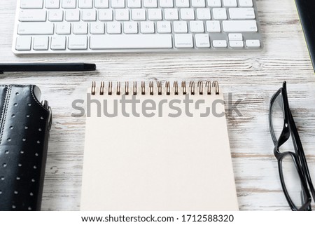 Still life of modern office workspace with supplies. Flat lay grunge wooden desk with computer keyboard and spiral notepad with pen. Time management and day planning. Corporate business concept.