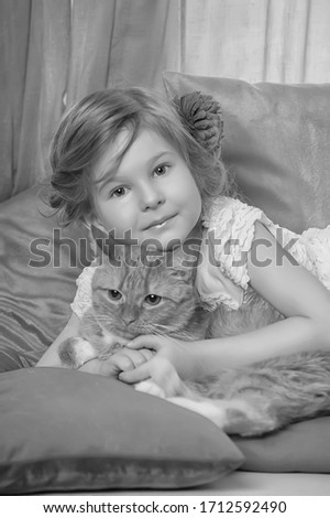 little girl hugging a big red cat