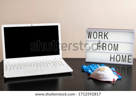 Photography of a home desktop during coronavirus quarantine and a light box with a message and medical ppe protections. Remote working. Telecommuting job.