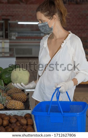 Woman wearing protective mask and latex gloves while grocery shopping in supermarket, Coronavirus contagion fears concept