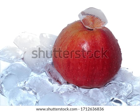 red ripe Apple of a rich color with blue ice cubes on a white background.