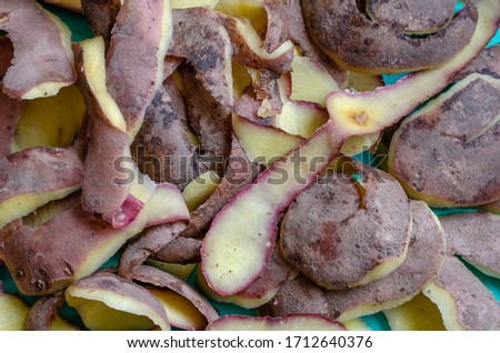 Peeling potatoes close-up. A pile of fresh peelings with potatoes on the table. Cooking process. Food waste. Selective focus.