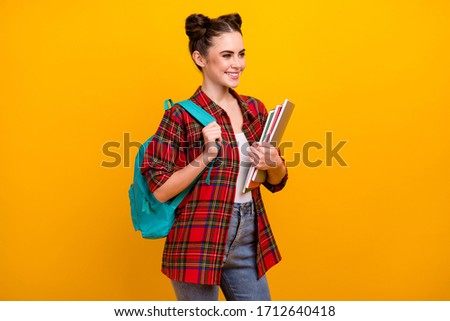 Photo of attractive student lady hold copybooks first study day college blue rucksack on shoulder good mood wear casual plaid shirt jeans isolated yellow color background