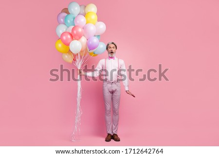 Full length body size view of his he nice attractive imposing comic childish cheerful cheery grey-haired man holding in hands bunch air balls isolated over pink pastel color background