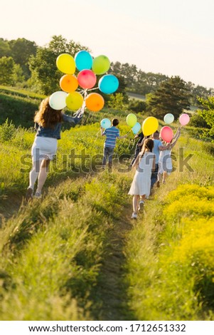 A large group of children have fun in nature. A lot of bright balloons, fun games, summer camp.