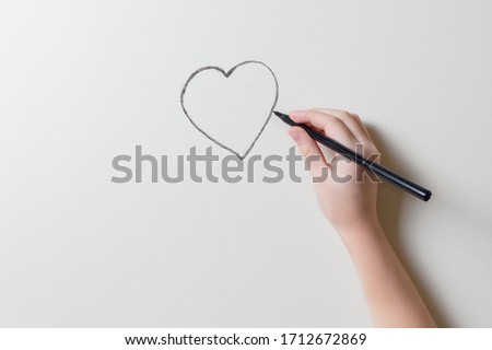 Girl's hand draws a heart on the wall of the room. Minimalistic photo with place for text and design. Life insurance, health and valentine's day concept