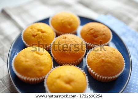 Pumpkin muffins on blue plate, selective focus. Homemade bakery, plant-based food, vegetable muffins, sweet dessert and napkin, blurred background
