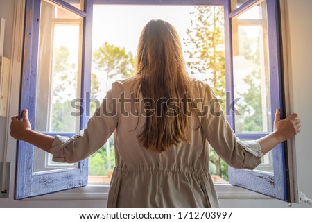 Coronavirus. Beautiful young woman isolated at home opening the window. Looking through the window. recovery from the infection. Quarantine. Isolated to prevent infection. Getting out from home. Royalty-Free Stock Photo #1712703997