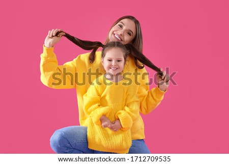 Young mother and little daughter on pink background