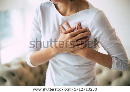 Heartache. Close-up photo of woman's hands lying on her chest because of her severe chest pain.