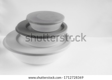 Plastic food containers of different sizes, black and white photo.