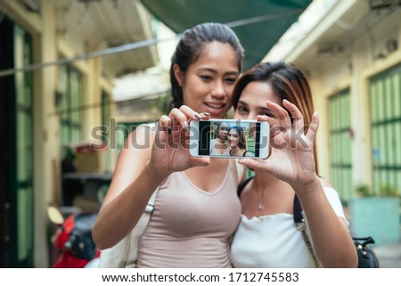 Two pretty smiling girls taking a selfie outdoors stock photo