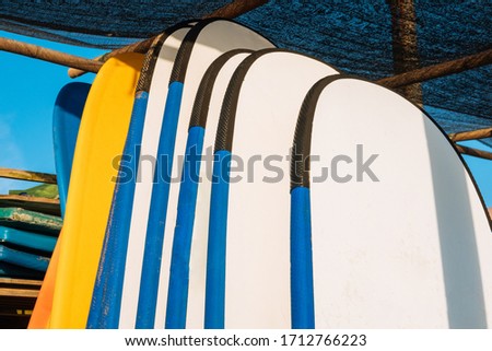 Close up stack of blue color soft surfboards in a stack by ocean.Bali.Indonesia. Surf boards on sandy beach for rent. Surf lessons on Weligama beach, Sri Lanka.