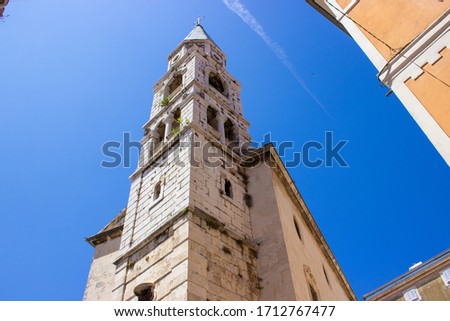 Picture of the Bell Tower of St. Elias' Church (or Church of St. Elias) in the old town of Zadar, Croatia, with a vapur trail in the sky at the background