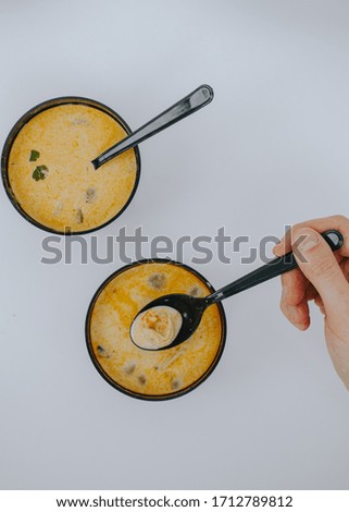 A man holds a spoon with Tom Yam soup. Food delivery