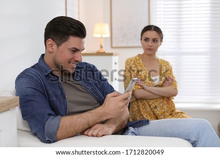 Man preferring smartphone over spending time with his girlfriend at home. Jealousy in relationship Royalty-Free Stock Photo #1712820049