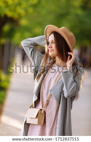 Beautiful young brunette woman with long hair flying in the wind and brown hat in park in summer. Head shot of gorgeous teenage girl with blue eyes. shallow depth of field