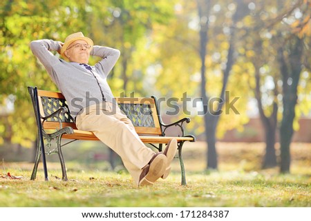 Senior gentleman sitting on a wooden bench and relaxing in a park Royalty-Free Stock Photo #171284387