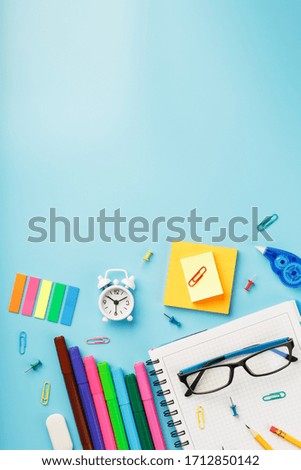 Colorful Stationery items with an alarm clock lie on a blue background.