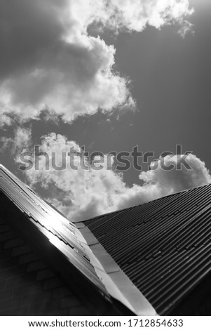 Roof made of stainless steel against the sunny cloudy sky, bw photo.