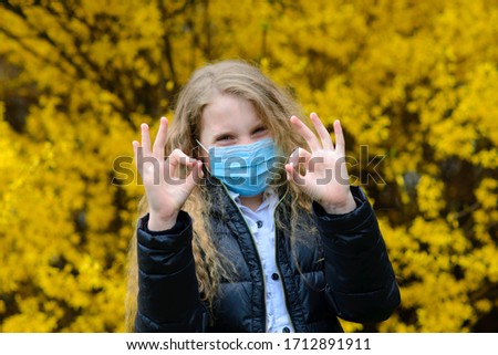 Portrait of sad caucasian child in face mask on closed playground outdoor. Coronavirus social distance quarantine.