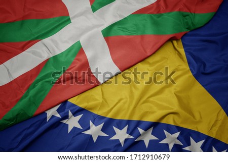 waving colorful flag of bosnia and herzegovina and national flag of basque country. macro
