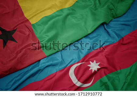 waving colorful flag of azerbaijan and national flag of guinea bissau. macro